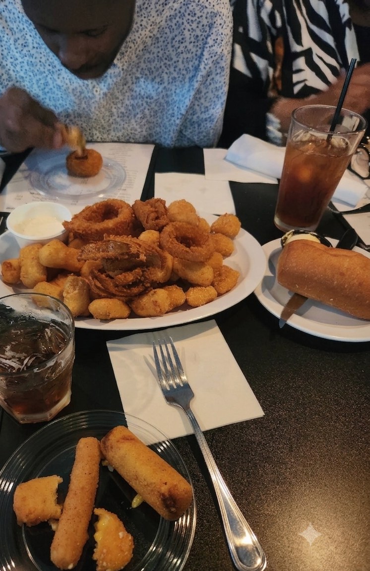 A sampler platter of onion rings, fried starters and cheese sticks, with iced tea