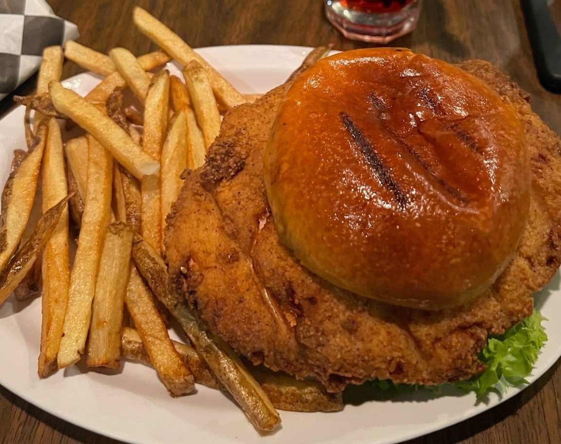 A chicken fried steak, golden and crisp, served with fries