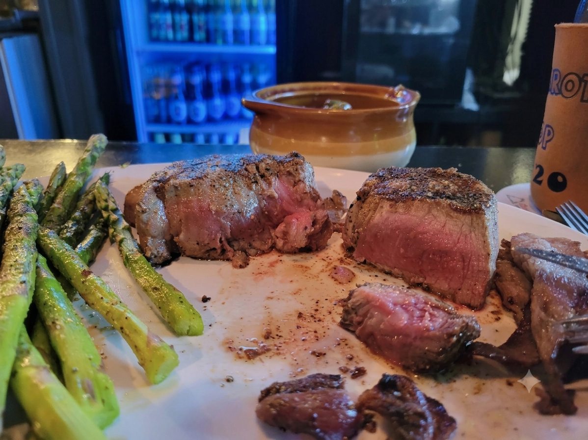 Filet mignon sliced open to a warm pink centre, served with grilled asparagus